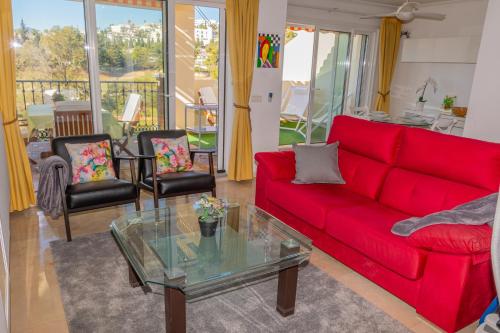 een woonkamer met een rode bank en een glazen tafel bij Appartement Limonar del Golf - Full Option in Mijas Costa