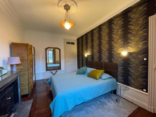 sypialnia z łóżkiem z niebieską pościelą i lustrem w obiekcie Maison Pignol w mieście Le Puy-en-Velay