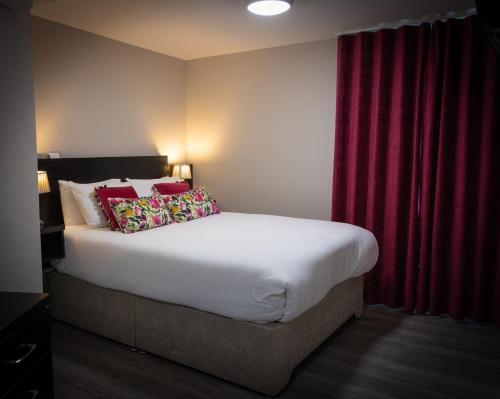 a bedroom with a large bed with red curtains at Behan's Horseshoe Bar & Restaurant in Listowel