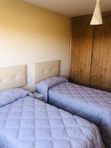 2 Betten in einem Zimmer mit blauer Bettwäsche in der Unterkunft Piso moderno in Sarria