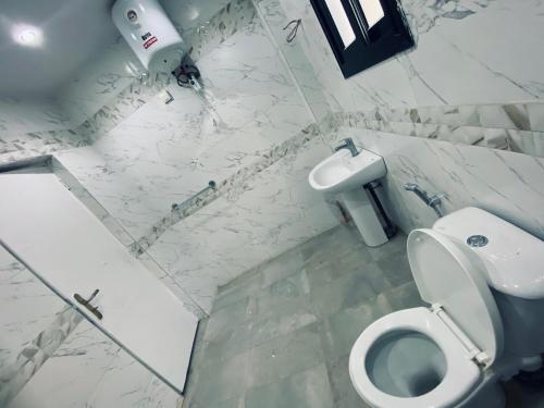 a white bathroom with a toilet and a sink at RESIDENCE EL HADJI in Dakar