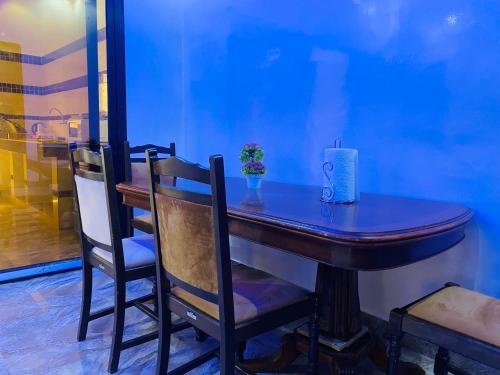 a blue room with a wooden table and chairs at RESIDENCE EL HADJI in Dakar