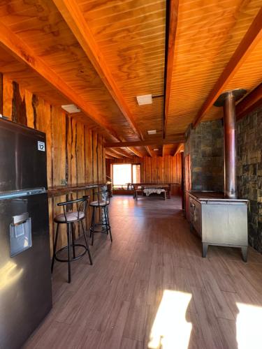 a large room with wooden walls and a kitchen with a refrigerator at Kumewe Lodge in Panguipulli