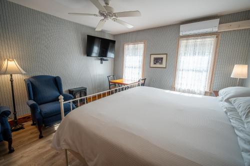 a bedroom with a large white bed and a blue chair at Albergo Allegria Hotel & Breakfast Restaurant in Windham