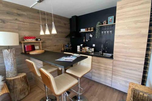 een keuken met een zwart aanrecht en een tafel met krukken bij Cute duplex in Chatel centre in Châtel