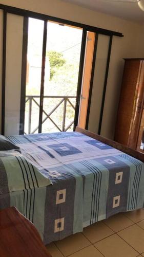 Bett in einem Zimmer mit einem großen Fenster in der Unterkunft Maison Bourg des Anses d'Arlet in Les Anses-dʼArlets