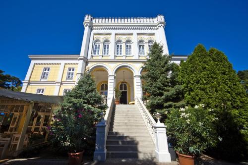 a large yellow building with stairs in front of it at Hotel Astoria in Balatonfüred
