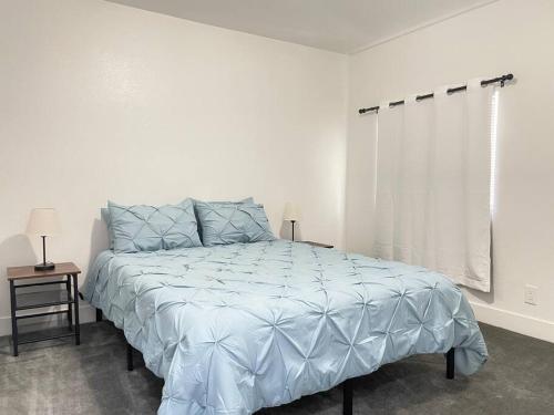 a bedroom with a bed with a blue comforter and a window at 3Bedroom 2Bath 15 Min to strip 10 downtown in Las Vegas