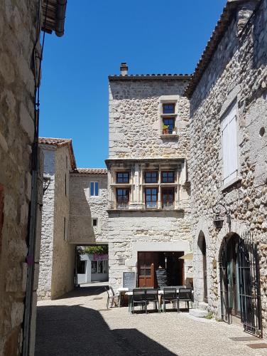 a stone building with tables and chairs in a courtyard at Maison du Baron - Centre historique de RUOMS in Ruoms