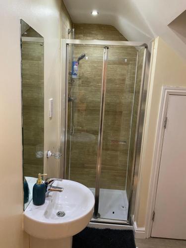 ein Bad mit einer Dusche und einem weißen Waschbecken in der Unterkunft Rehoboth guest house in Manchester