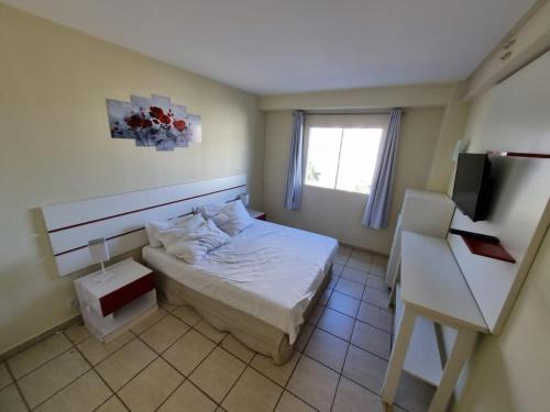 a small bedroom with a bed and a window at Apartamento Giardino 212 sem parques in Rio Quente
