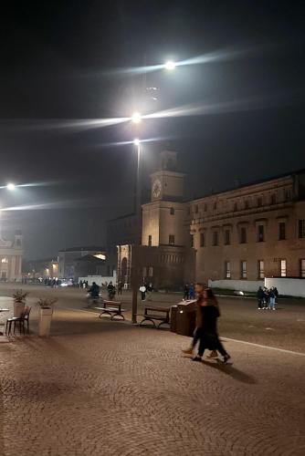 a couple of people walking in front of a building at night at Il sole in Carpi