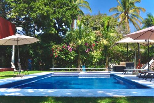 una piscina con sillas y sombrillas junto a ella en Quinta del Rocío Casa Tropical en Ticuman, en Ticumán