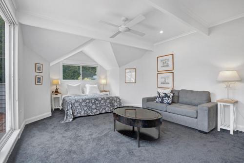 a bedroom with a bed and a couch and a table at Iluka Palm Cove Penthouse in Palm Beach