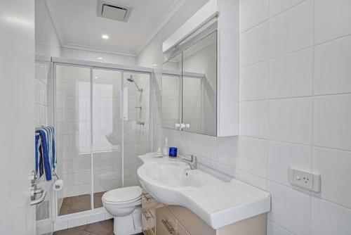 a white bathroom with a sink and a toilet at Iluka Palm Cove Penthouse in Palm Beach