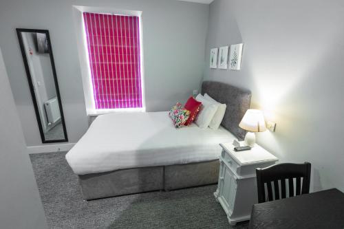 a small bedroom with a bed and a window at Behan's Horseshoe Bar & Restaurant in Listowel
