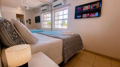 a bedroom with a bed and a tv on the wall at Casa Vila da Praia Buzios - Centro in Búzios