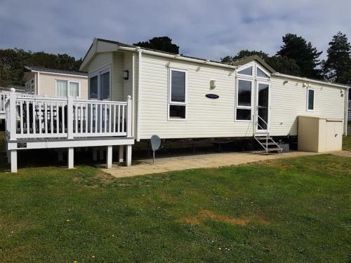 a white mobile home with a porch and a yard at Home from Home cosy caravan in Bembridge