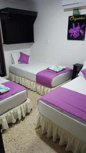 three beds in a room with purple pillows at Casa Villavicencio in Villavicencio