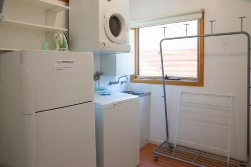 a small kitchen with a refrigerator and a window at Settlement Lodge in Mount Buller