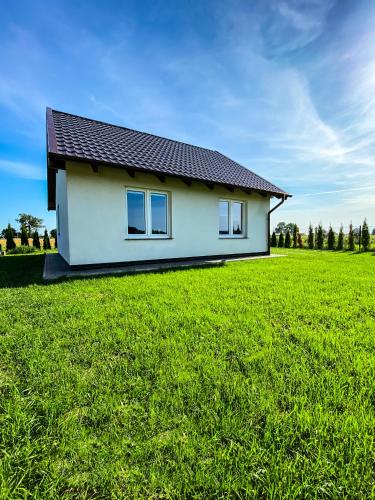 mały biały dom na polu trawy w obiekcie Nadmorska Kępa w Kątach Rybackich