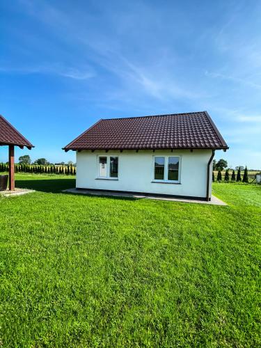 a white house with a red roof on a green field at Nadmorska Kępa in Kąty Rybackie