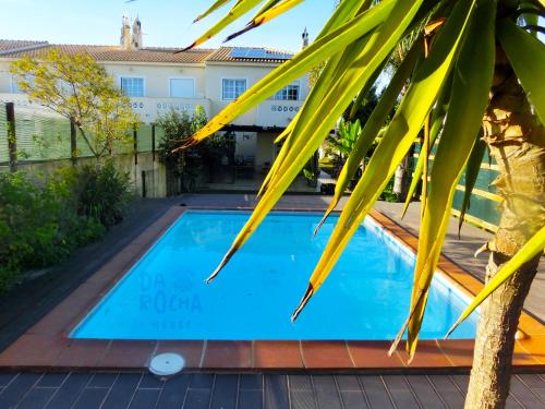 a swimming pool in front of a house with a palm tree at Da Rocha House in Parchal