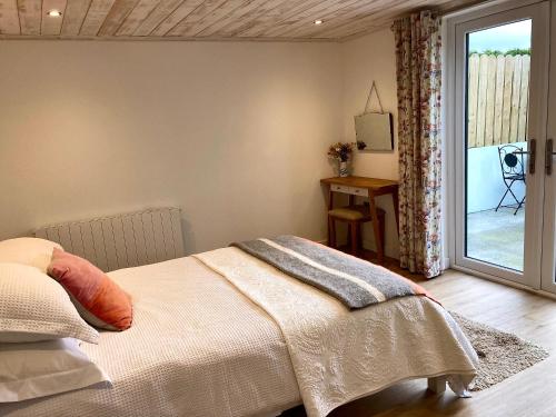 Schlafzimmer mit einem Bett und einer Glasschiebetür in der Unterkunft The Birdhouse with Hot Tub in Gortahork