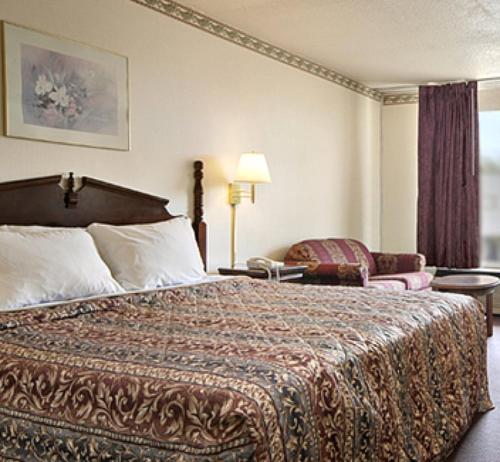 a hotel room with a large bed and a chair at Royal Extended Stay in Alcoa