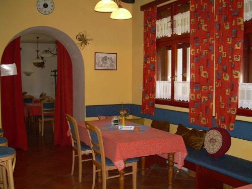 a dining room with a table and chairs with red curtains at Penzion U Ráztoky in Rusava