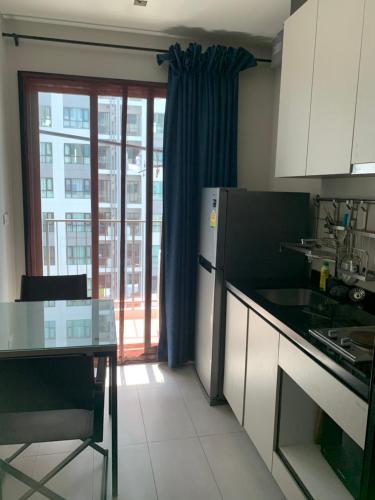 a kitchen with a refrigerator and a table and a window at the base in Pattaya Central