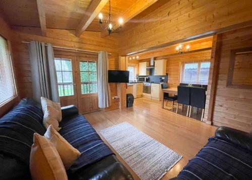 uma sala de estar com um sofá preto e uma cozinha em Oathill Farm Lodges em Winsham