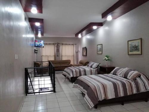 een grote kamer met 2 bedden en een bank bij Estudio casa del minero in Hidalgo del Parral