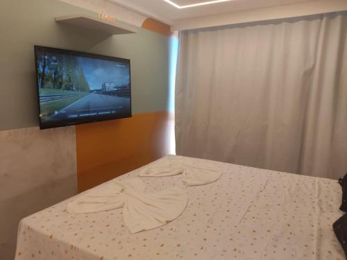 a bedroom with a bed with a tv on the wall at Luar Porto de Galinhas in Porto De Galinhas