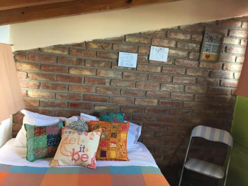 1 dormitorio con pared de ladrillo y cama con almohadas en Departamento Privado en Gran Mendoza en Godoy Cruz
