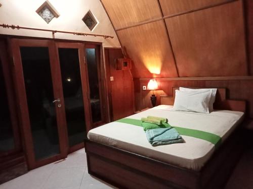 a bedroom with a bed with a green towel on it at Meno Smile Cottages in Gili Meno