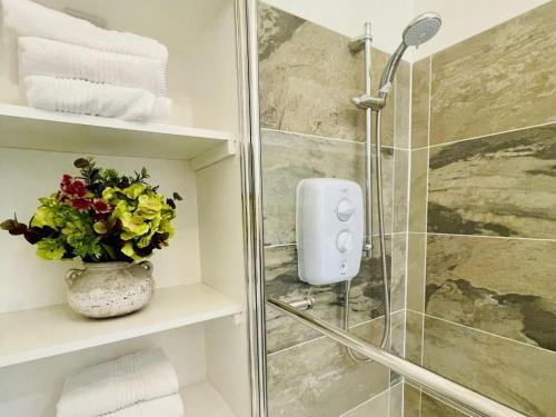 a bathroom with a shower and a vase of flowers at Bank Garden Cottage in Fortrose