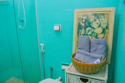 a bathroom with a basket of towels and a picture at Dois em cena - apartamento aconchegante e tranquilo no Centro do Rio in Rio de Janeiro