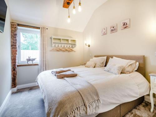 a bedroom with a large white bed with a window at Cattle Crush Cottage - Uk35988 in Great Driffield