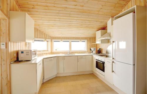 a kitchen with white appliances and a wooden ceiling at Four-Bedroom Holiday Home In Allinge in Allinge