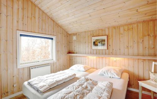 two beds in a room with wooden walls and a window at Cozy Home In Allinge With Sauna in Allinge