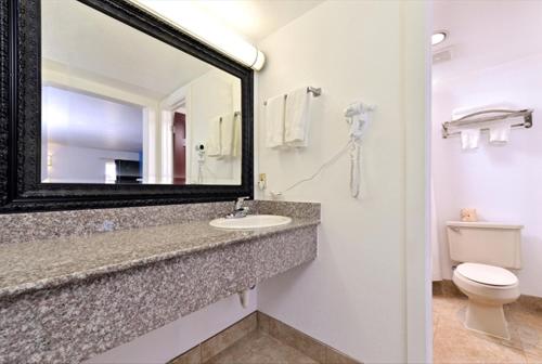 a bathroom with a sink and a mirror and a toilet at Executive Inn in Edmond