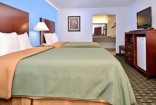 a hotel room with two beds and a flat screen tv at Executive Inn in Edmond