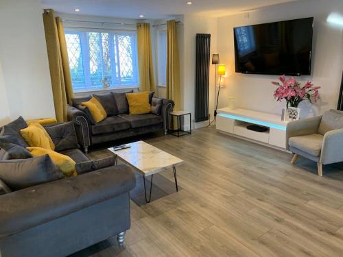 a living room with couches and a flat screen tv at Luxury Modern house Open Plan Living Space&hottub sleeps 6 in Penmaen-mawr