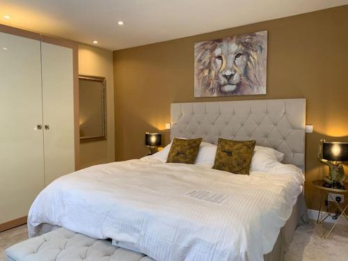 a bedroom with a large white bed with a lion painting on the wall at Luxury Modern house Open Plan Living Space&hottub sleeps 6 in Penmaen-mawr