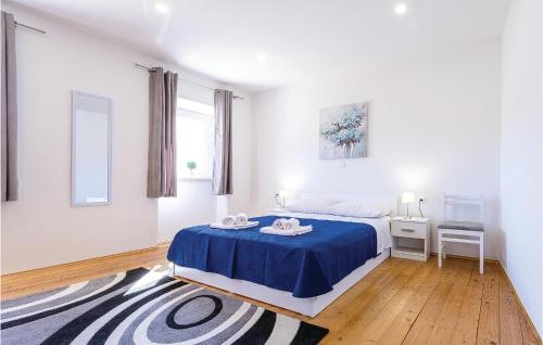 3 Bedroom Gorgeous Home In Mrcevo في Mrčevo: غرفة نوم بيضاء مع سرير وبطانية زرقاء
