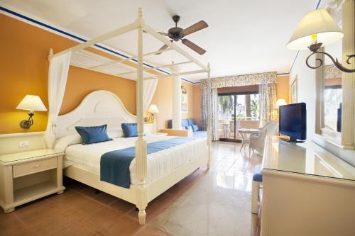 ein Schlafzimmer mit einem Bett und einem TV in einem Zimmer in der Unterkunft Bahia Principe Grand Punta Cana - All Inclusive in Punta Cana