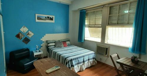 1 dormitorio con paredes azules, 1 cama y 1 mesa en Sweet Studio Lapa, en Río de Janeiro