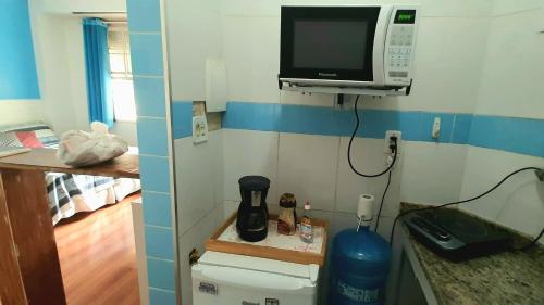 una pequeña cocina con microondas y una habitación en Sweet Studio Lapa, en Río de Janeiro