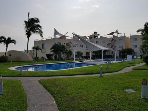 un complexe avec une piscine en face d'un bâtiment dans l'établissement Acapulco diamante departamento con playa ecológico, à Acapulco